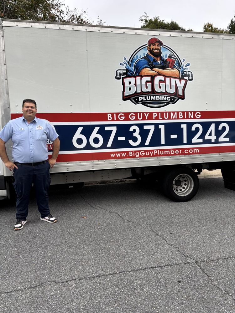 MJ smiling in his Big Guy Plumbing uniform next to the company truck
